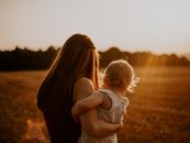 Back view photo of a woman in black sleeveless top carrying a toddler