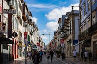 在葡萄牙波尔图热闹的街景中，商店和行人沐浴在明亮的蓝天下