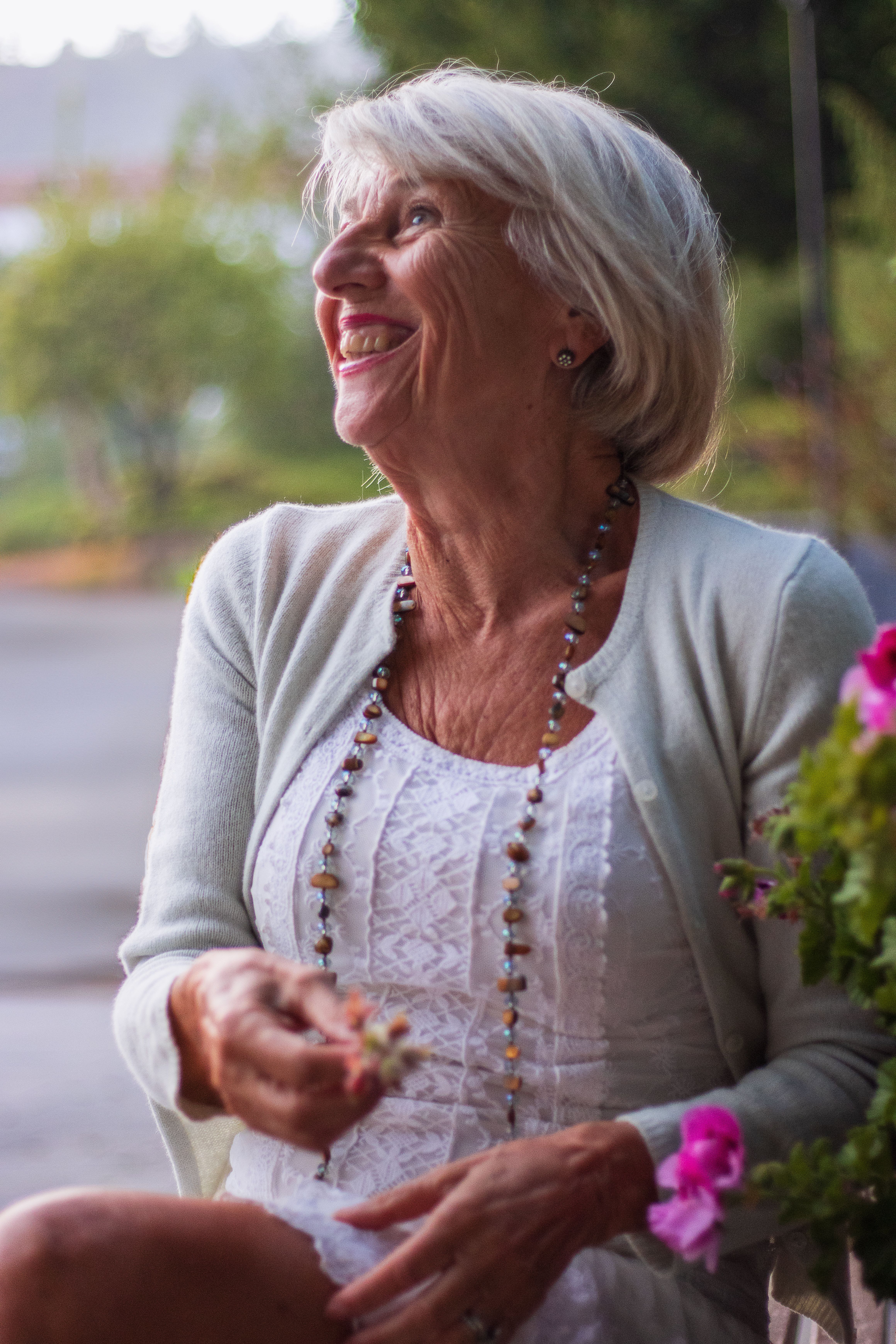 Smiling senior woman sitting outdoors, enjoying a peaceful moment in the garden.