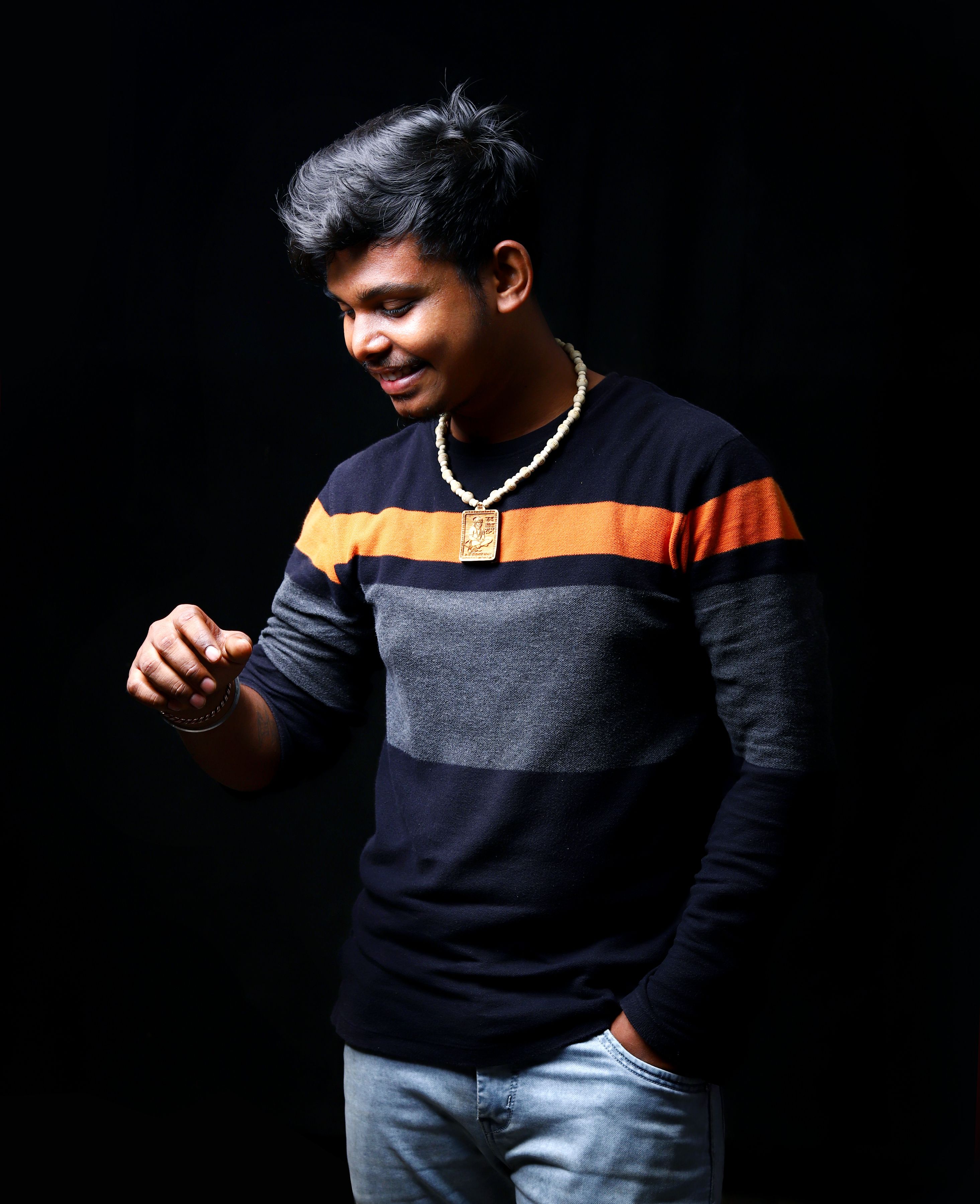 Stylish portrait of a smiling man wearing casual clothing against a black background, indoors.