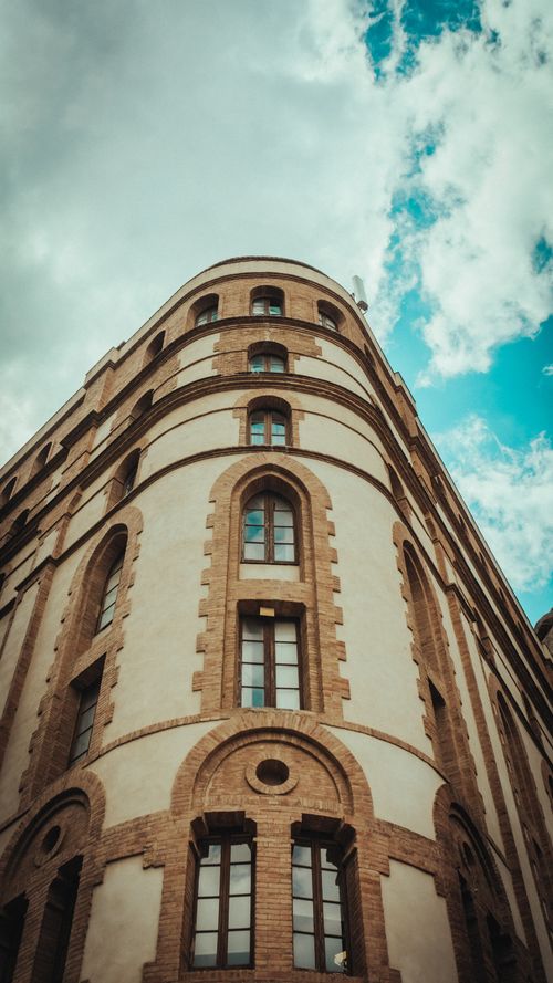 Free Low-angle shot of a historic building facade with a dramatic sky in Spain. Stock Photo
