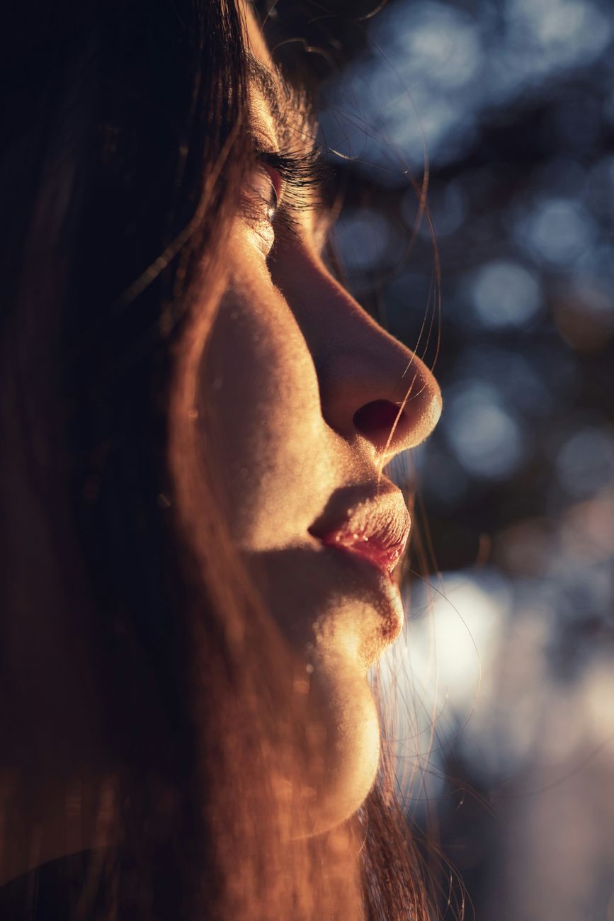 Close-up side profile of a young woman in warm sunset light with bokeh background.