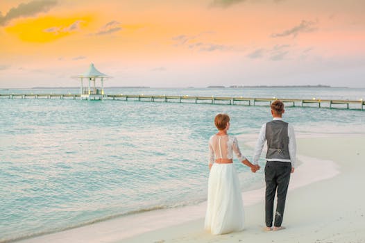 日落时分，新娘和新郎手牵着手，漫步在宁静的海滩上