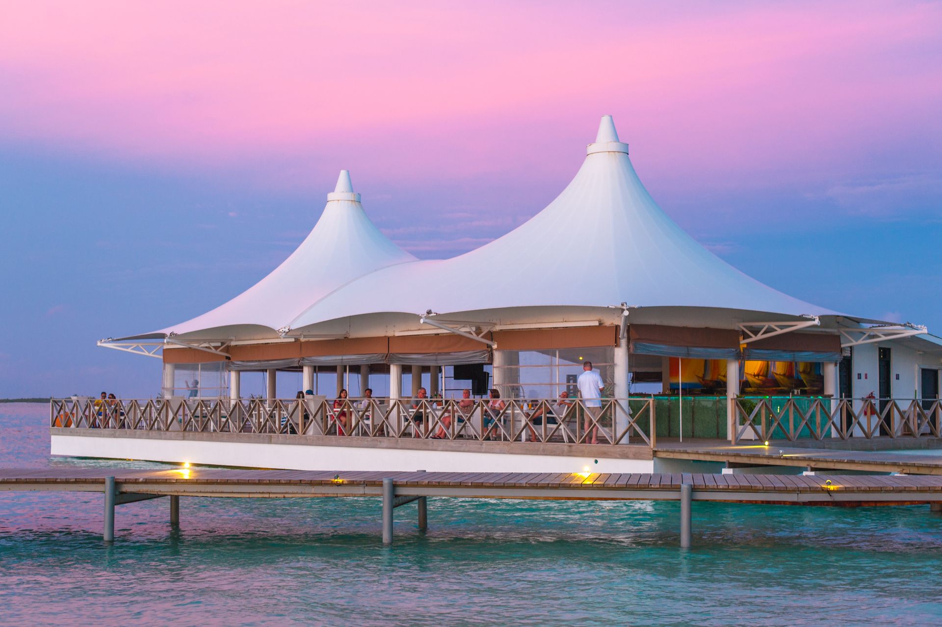 Luxurious gazebo on a dock with pink sunset sky, ideal for weddings and events.