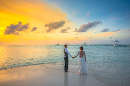 Free Man and Woman holding hands while Standing on the seashore Stock Photo