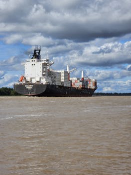Large cargo ship navigating open waters under a dramatic cloudy sky, emphasizing global trade.