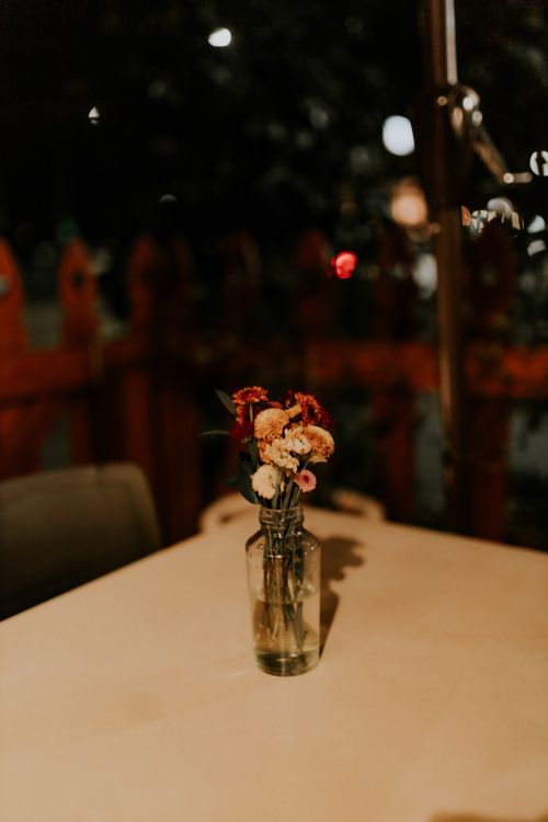 Free A cozy evening restaurant setting with a simple floral arrangement in a glass bottle on the table. Stock Photo