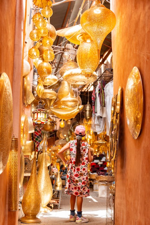 A woman walking through a narrow alleyway with lots of gold and silver decorations