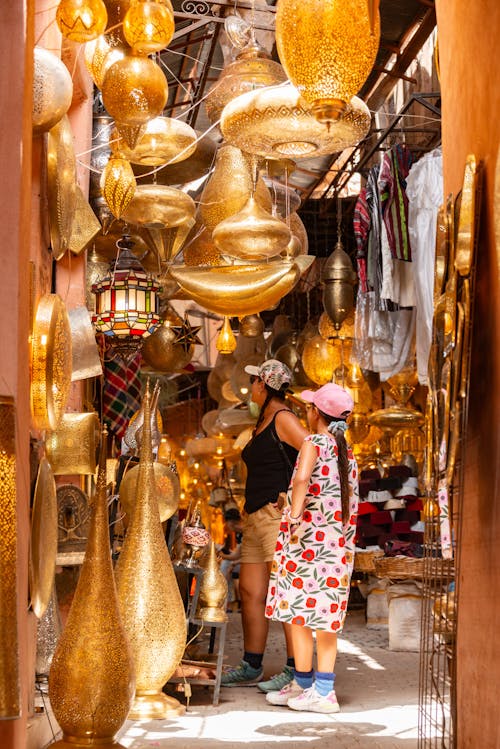 A woman walking through a narrow alley with many gold items