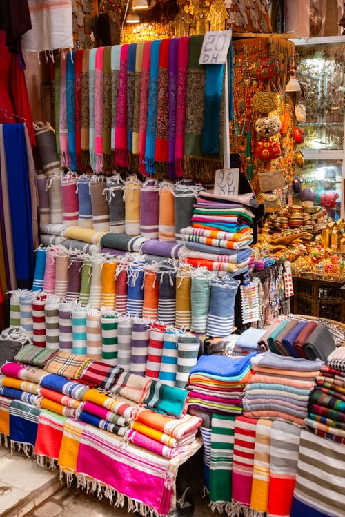 Free Vibrant array of scarfs and textiles displayed at a traditional market stall. Stock Photo