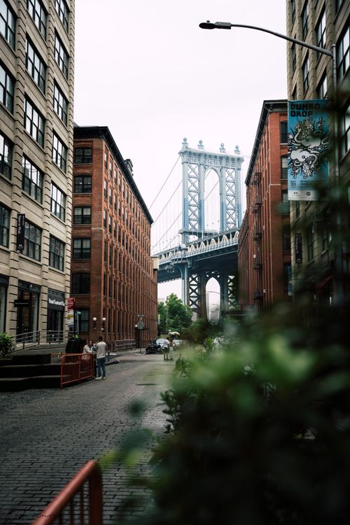 Free Stunning view of the Manhattan Bridge seen between classic New York City buildings on a cobbled street. Stock Photo