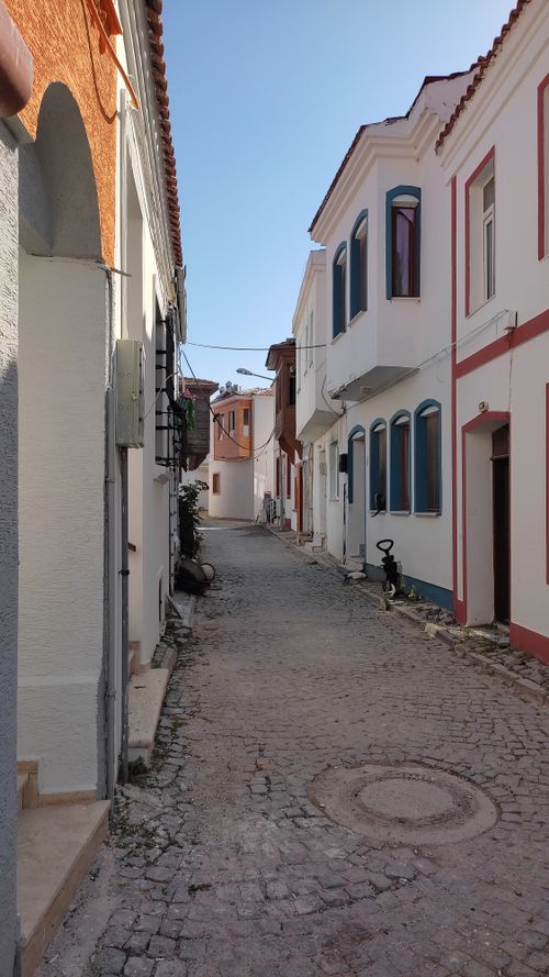 Free Narrow street with cobblestone path lined by vibrant houses under clear blue sky. Stock Photo