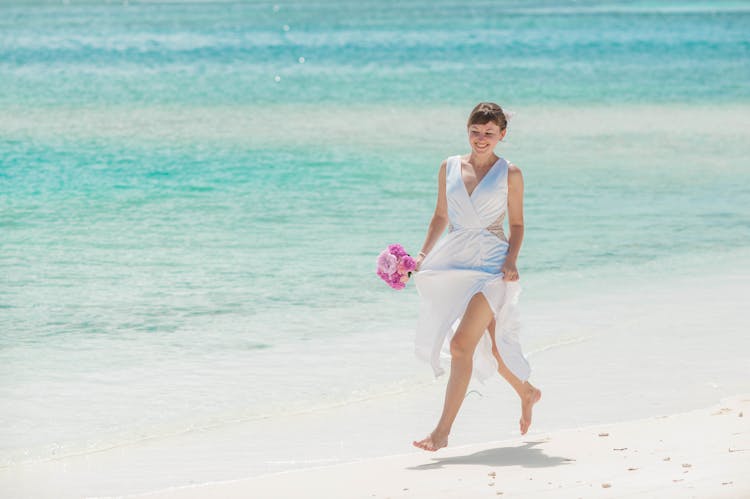 Woman In White Dress Running On The Beach