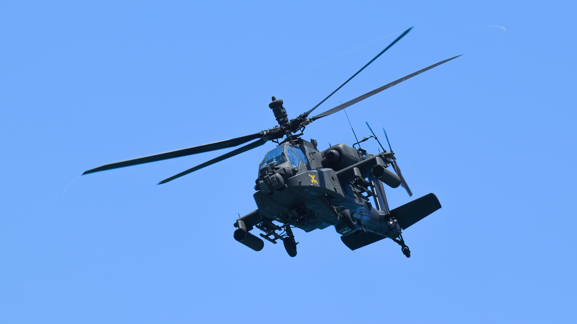 An advanced military helicopter flying high over Miami with a clear blue sky backdrop.