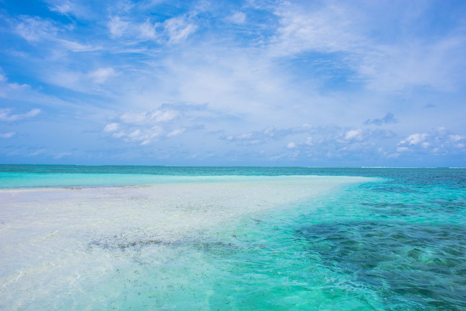 Shallow sandbar where pale turquoise water meets a deeper blue sea
