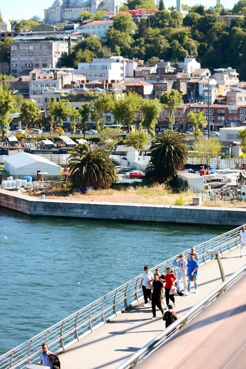 People walking on a bridge over water with a city in the background