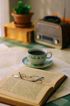 An inviting reading nook with an open book, coffee cup, and vintage radio.