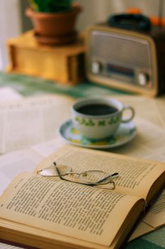 Open book and eyeglasses beside coffee in a cozy vintage setting. Perfect for relaxation.