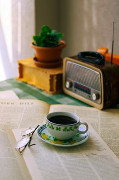 A vintage coffee scene with open books, radio, and potted plant, perfect for a relaxed morning ambiance.