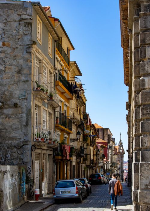 Free A scenic narrow street in Porto, Portugal, lined with historic buildings and cobblestone path on a sunny day. Stock Photo