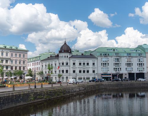 Free Charming waterfront scene with historic architecture and river under a vibrant blue sky with clouds. Stock Photo