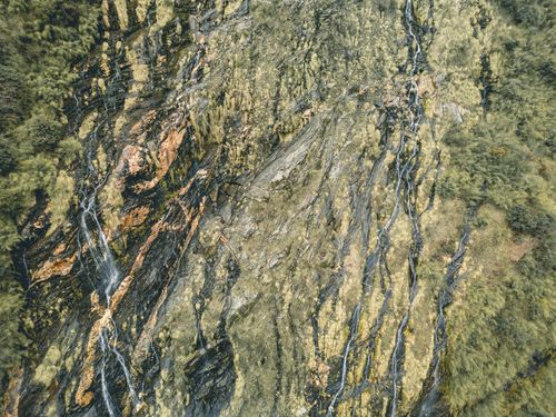 Free A stunning aerial view capturing the intricate waterfall patterns on a rocky hillside in Lwang Ghalel, Nepal. Stock Photo