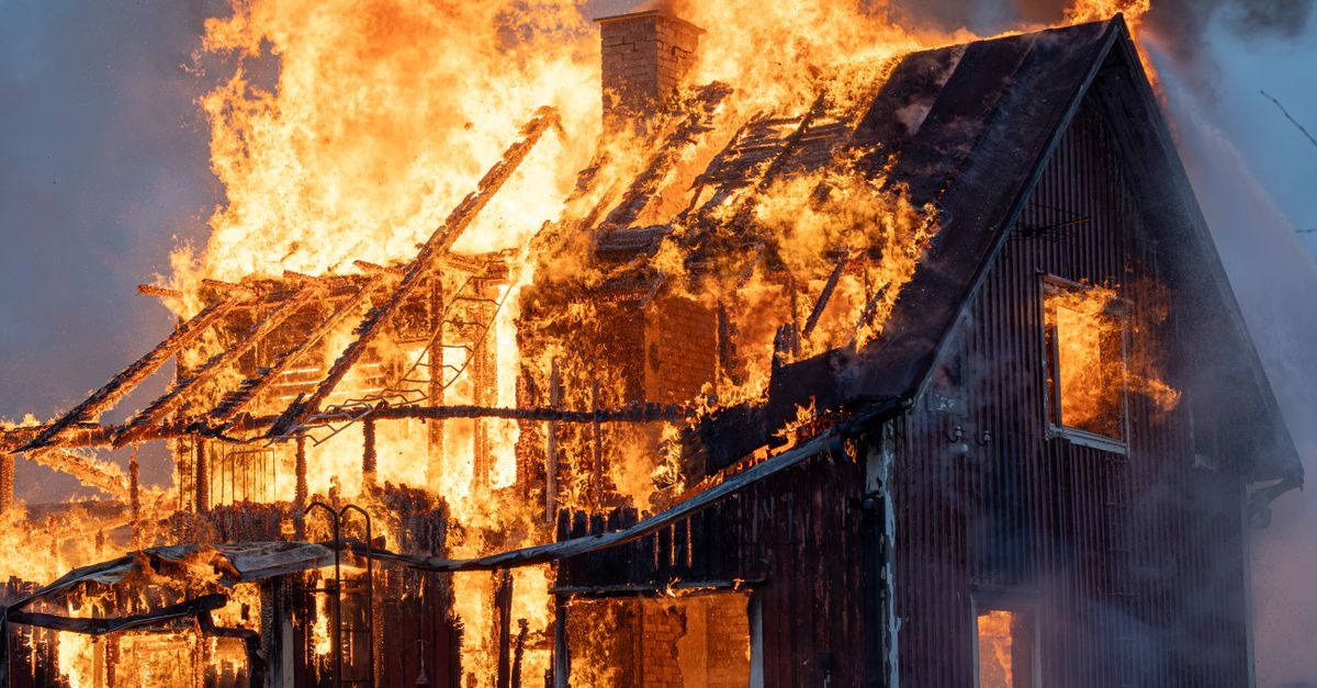 A house consumed by intense flames and smoke, capturing the power of fire.