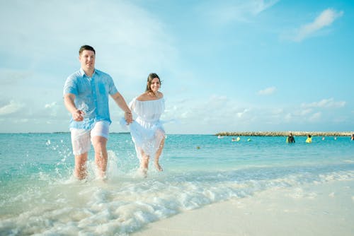 Free Man and Woman Running on Seashore Stock Photo