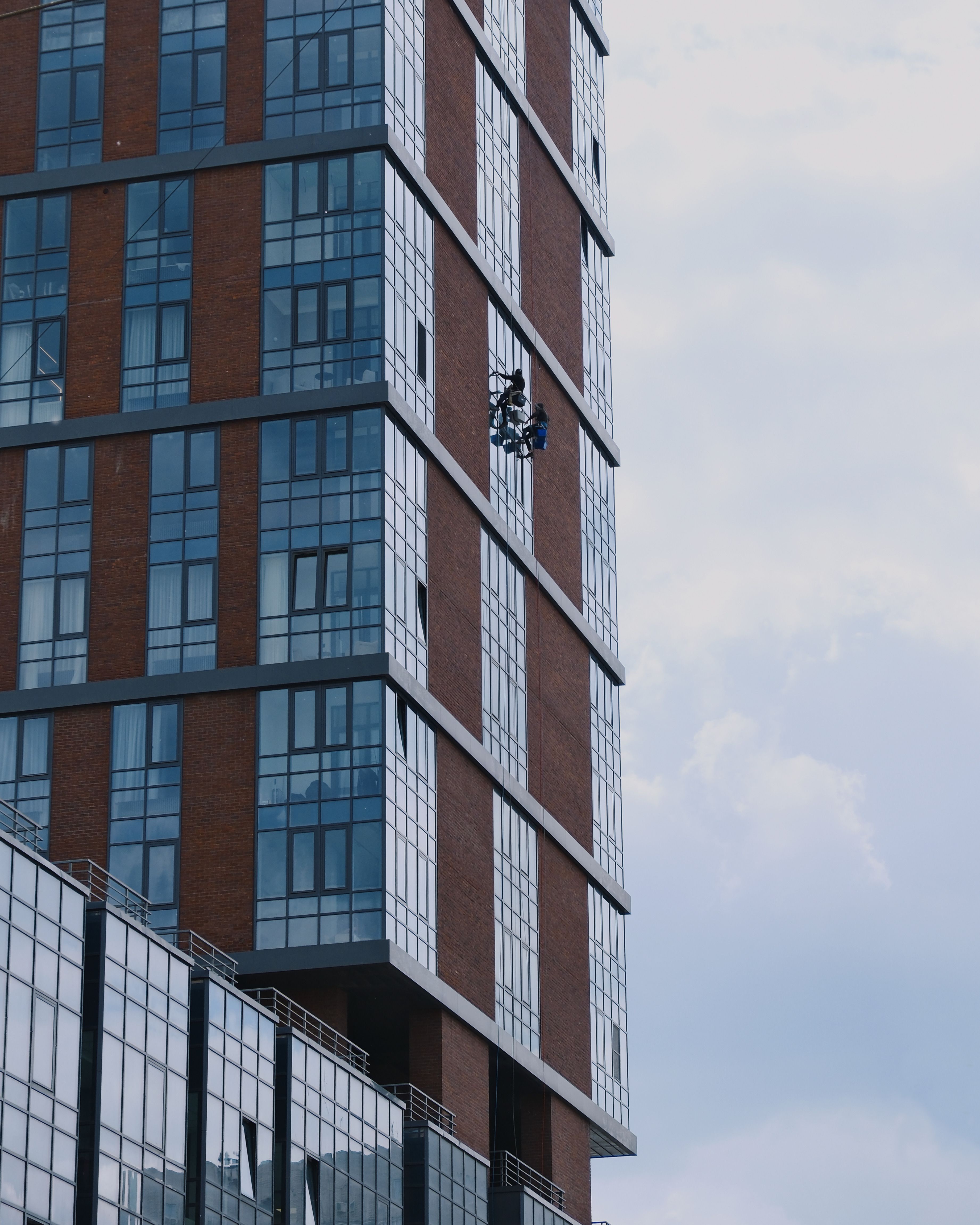 Window cleaners on a modern skyscraper in Rostov-on-Don, showcasing urban architecture.