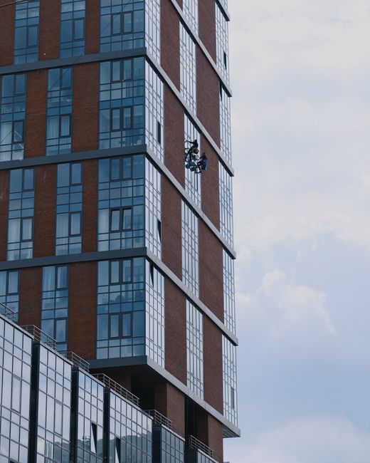 Window cleaners on a modern skyscraper in Rostov-on-Don, showcasing urban architecture.