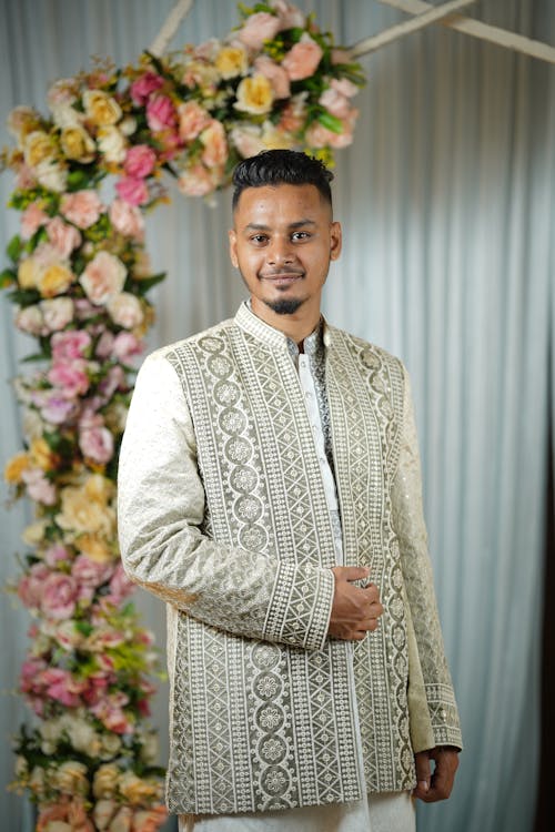 A man in a white sherwani and gold jacket