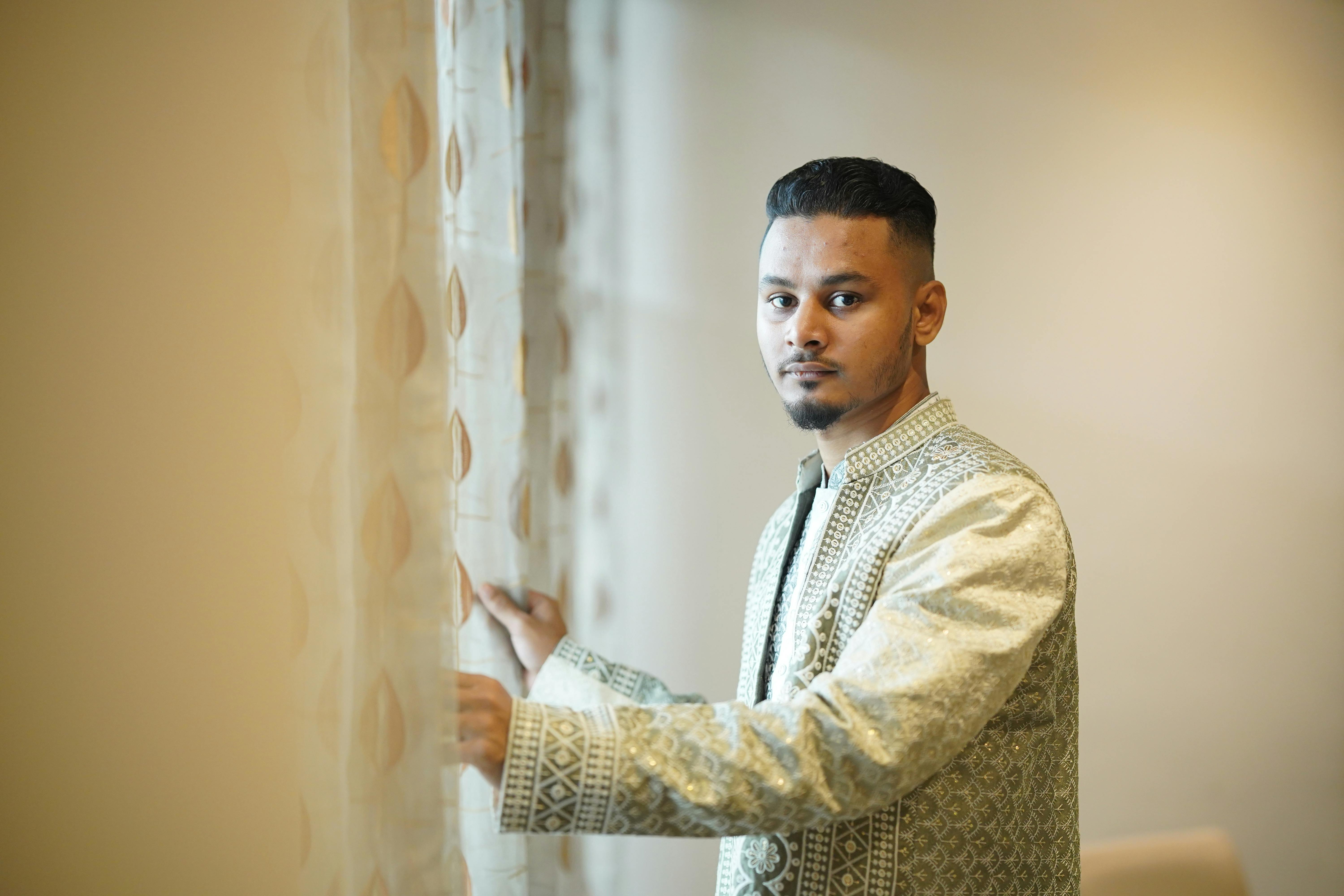 Elegant portrait of a groom in traditional attire by a window in Sylhet, Bangladesh.