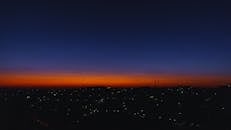 城市景观之上，令人惊叹的日落创造出戏剧性的天际线，下方灯光闪烁