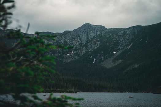 Serene view of a mountain and lake in Gaspé, QC, Canada under cloudy skies.
