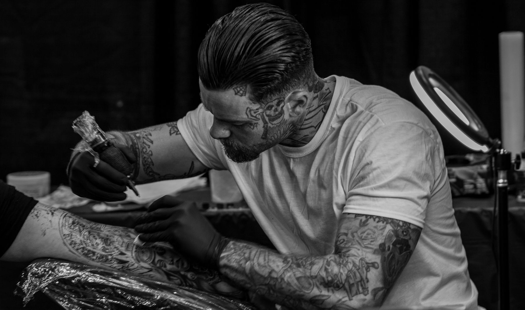Tattoo artist working on a client's arm — Black Heart Club studio