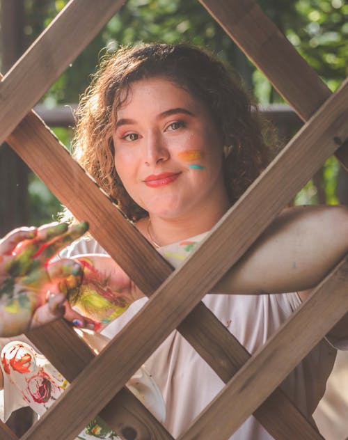 A woman with her hands painted in a wooden fence