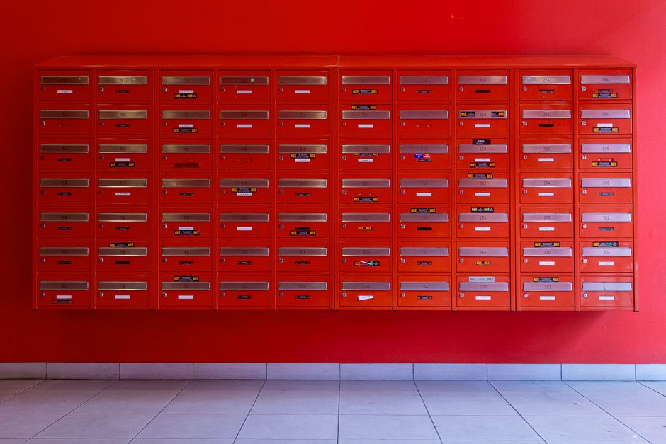 A vibrant wall of red mailboxes in an urban building, ideal for residential or commercial use.