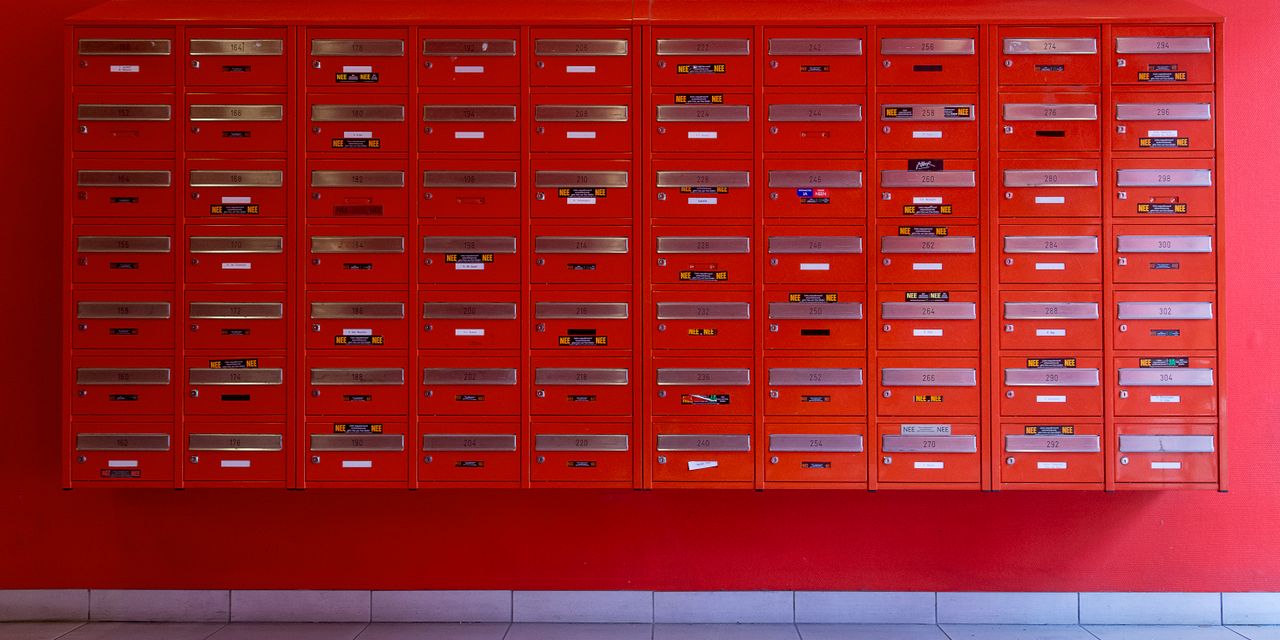 A vibrant wall of red mailboxes in an urban building.