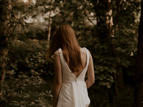Free Back View Photo of Woman in White Dress Walking in the Woods Stock Photo