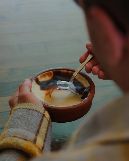 A person eating a bowl of coffee with a spoon