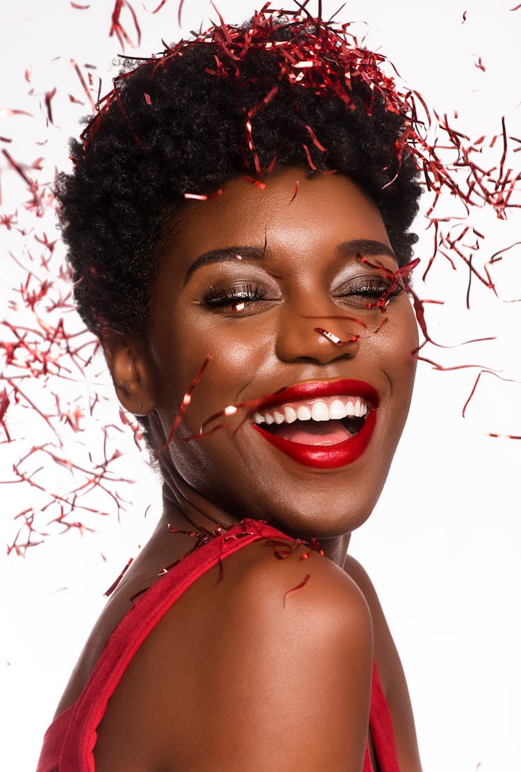 Close-up Photo Of Smiling Woman With Her Eyes Closed Posing As Confetti Drops Down Her Face