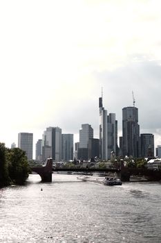 Scenic view of Frankfurt's modern skyline featuring skyscrapers and a bridge over the river.