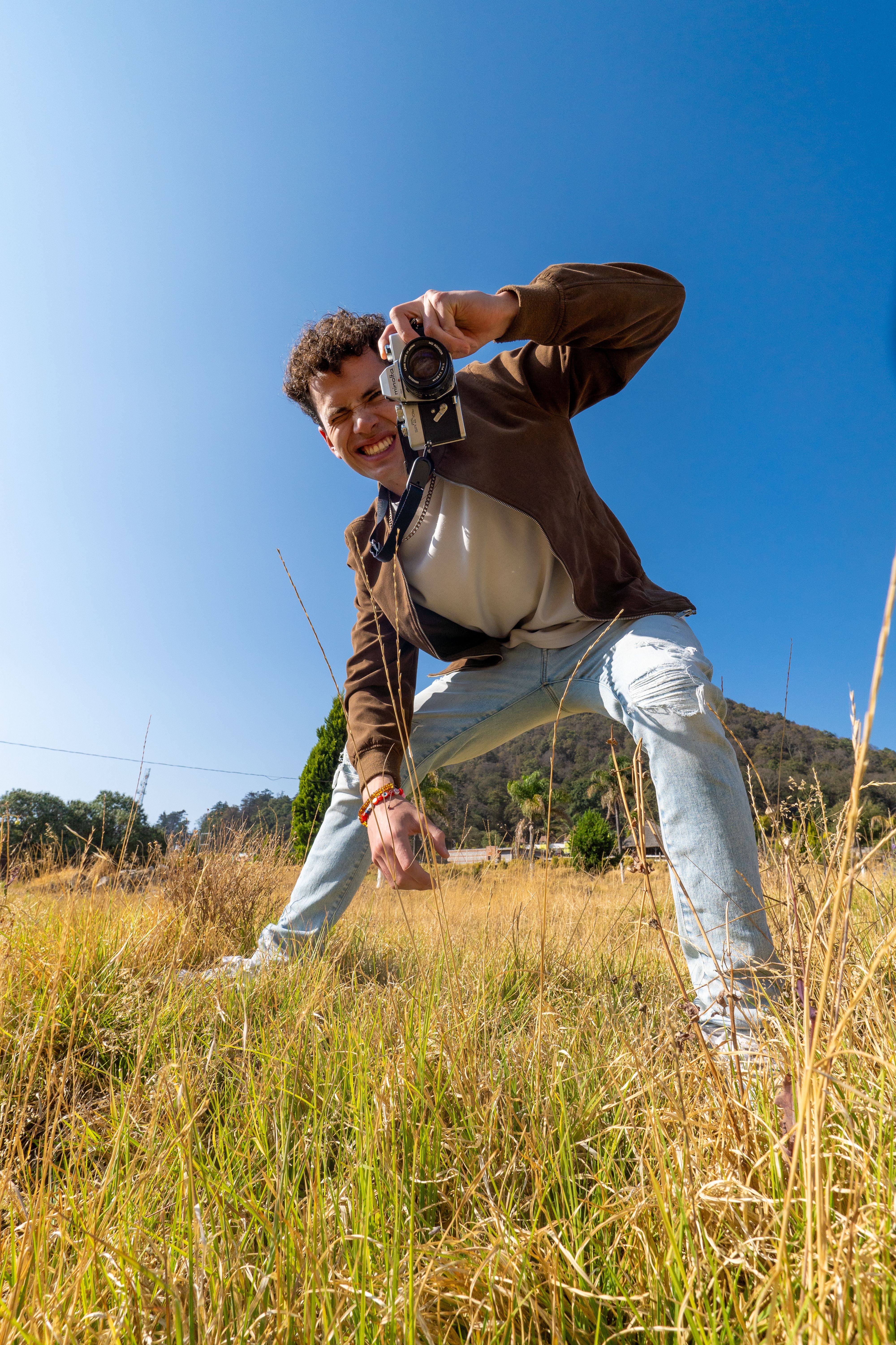 A young man poses with a camera in a sunlit field in Amecameca, Mexico.