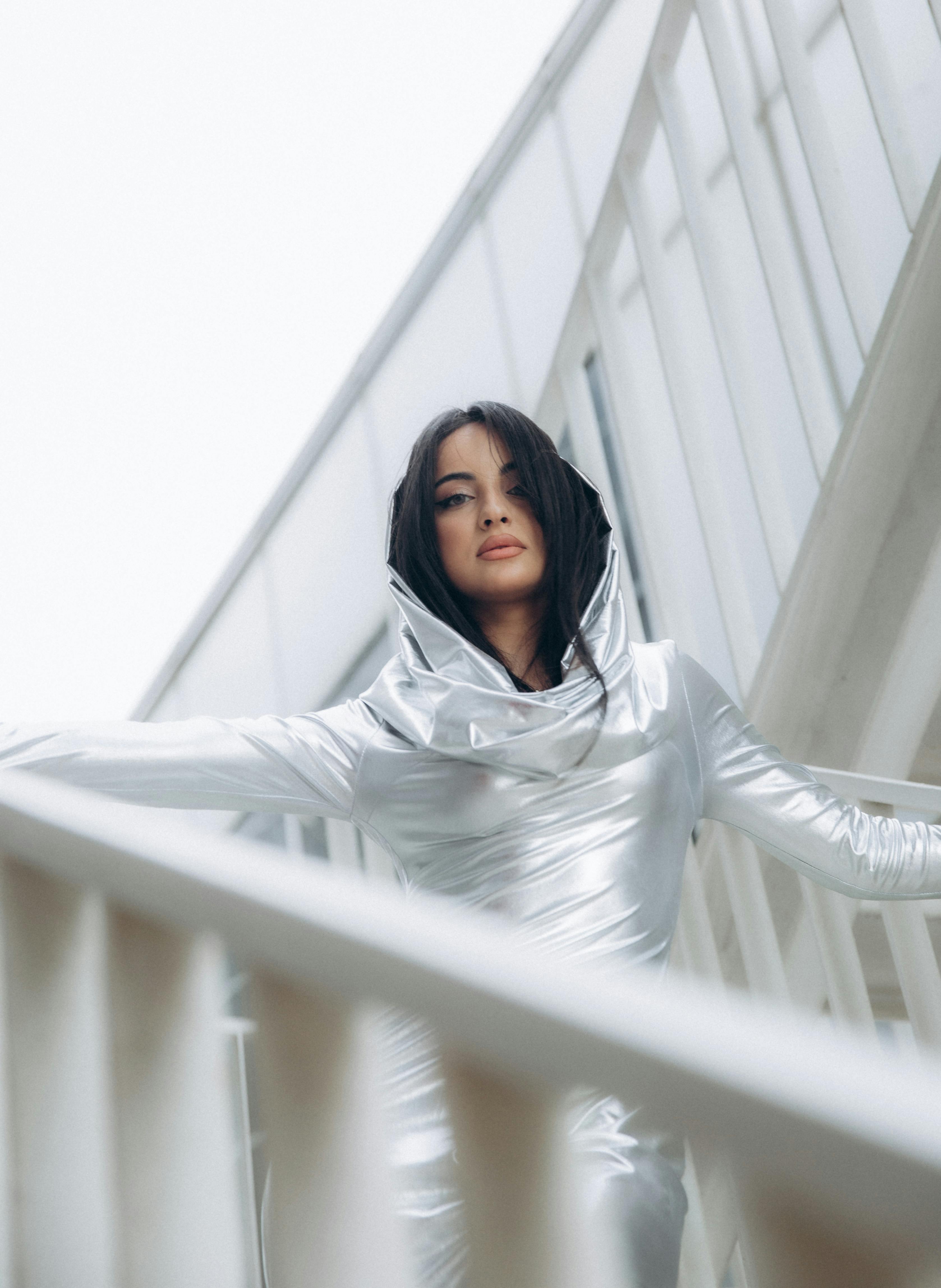 Free Fashionable woman in silver outfit posing on urban stairs, low angle view. Stock Photo