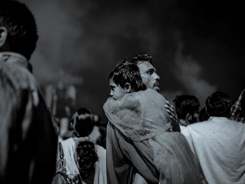 Free Emotional black and white scene of a father holding his daughter amidst a gathering at night. Stock Photo