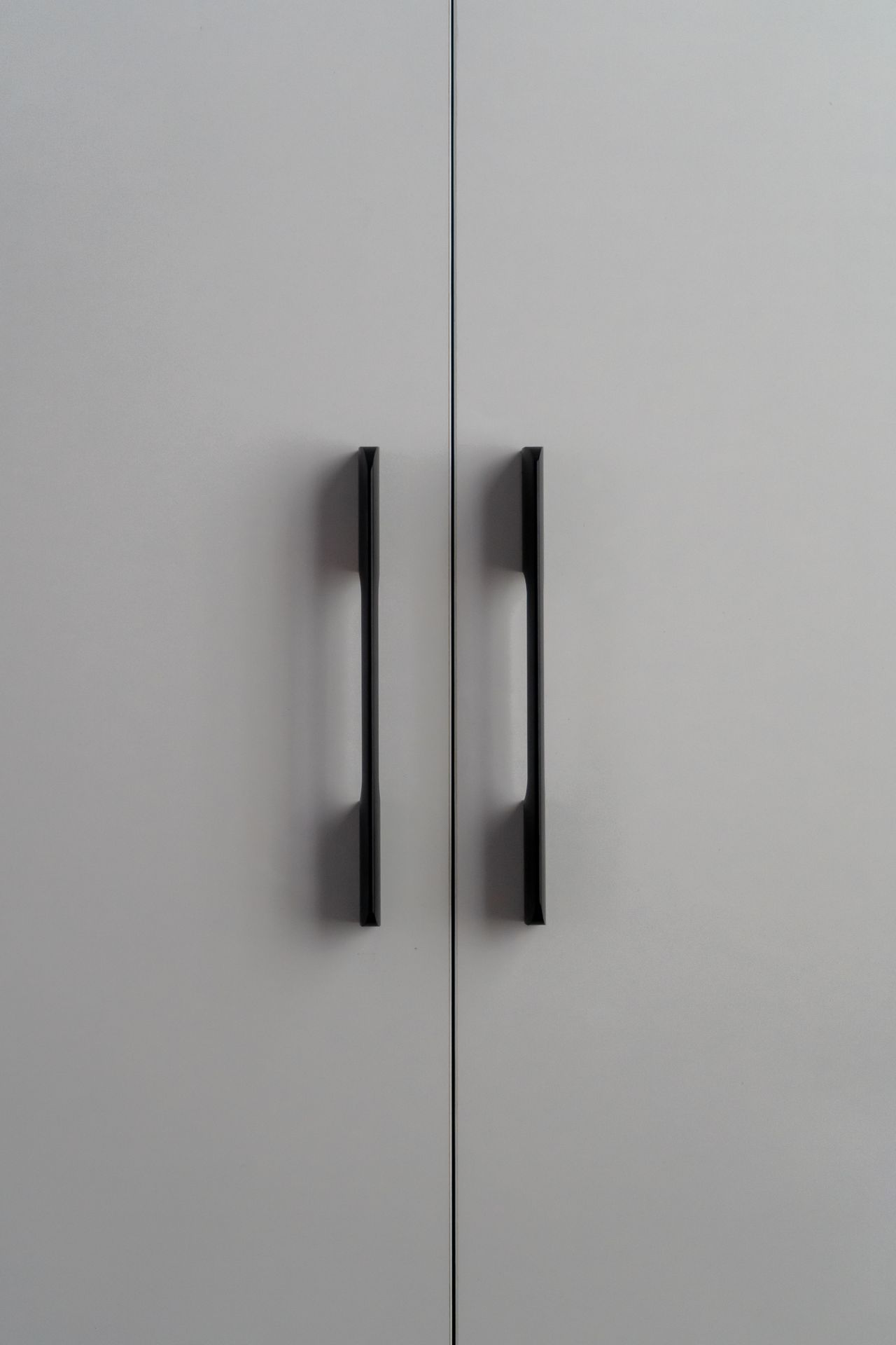 Close-up of white closet doors with slim black bar handles