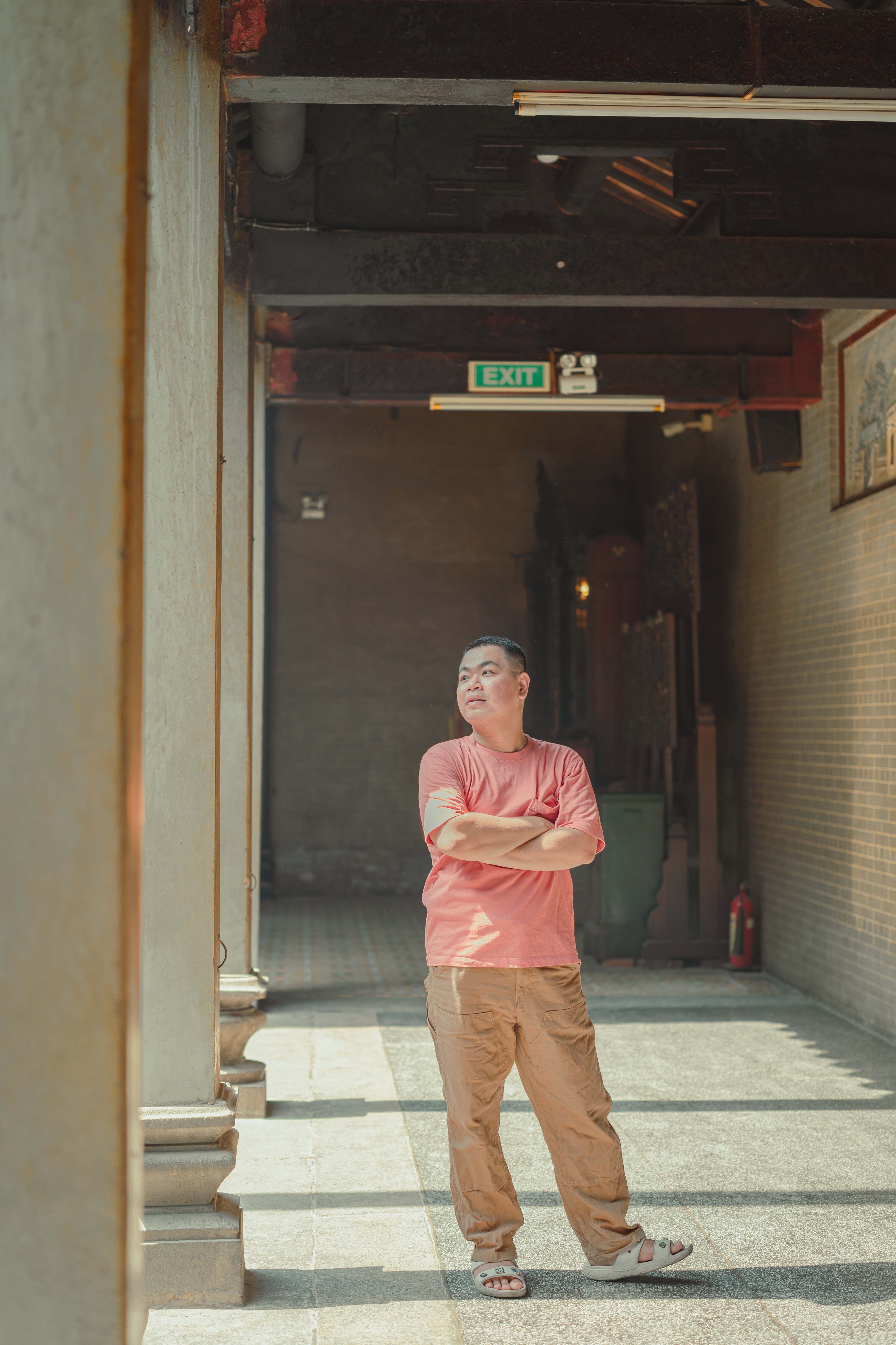 Asian man standing confidently in a sunlit corridor in Ho Chi Minh City, Vietnam.