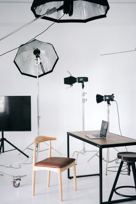 Modern photography studio with lighting equipment and a laptop on a desk.