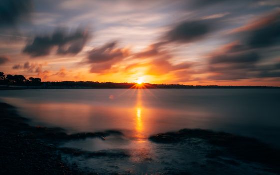 Captivating sunset over Christchurch coast with vibrant colors reflecting on the sea.