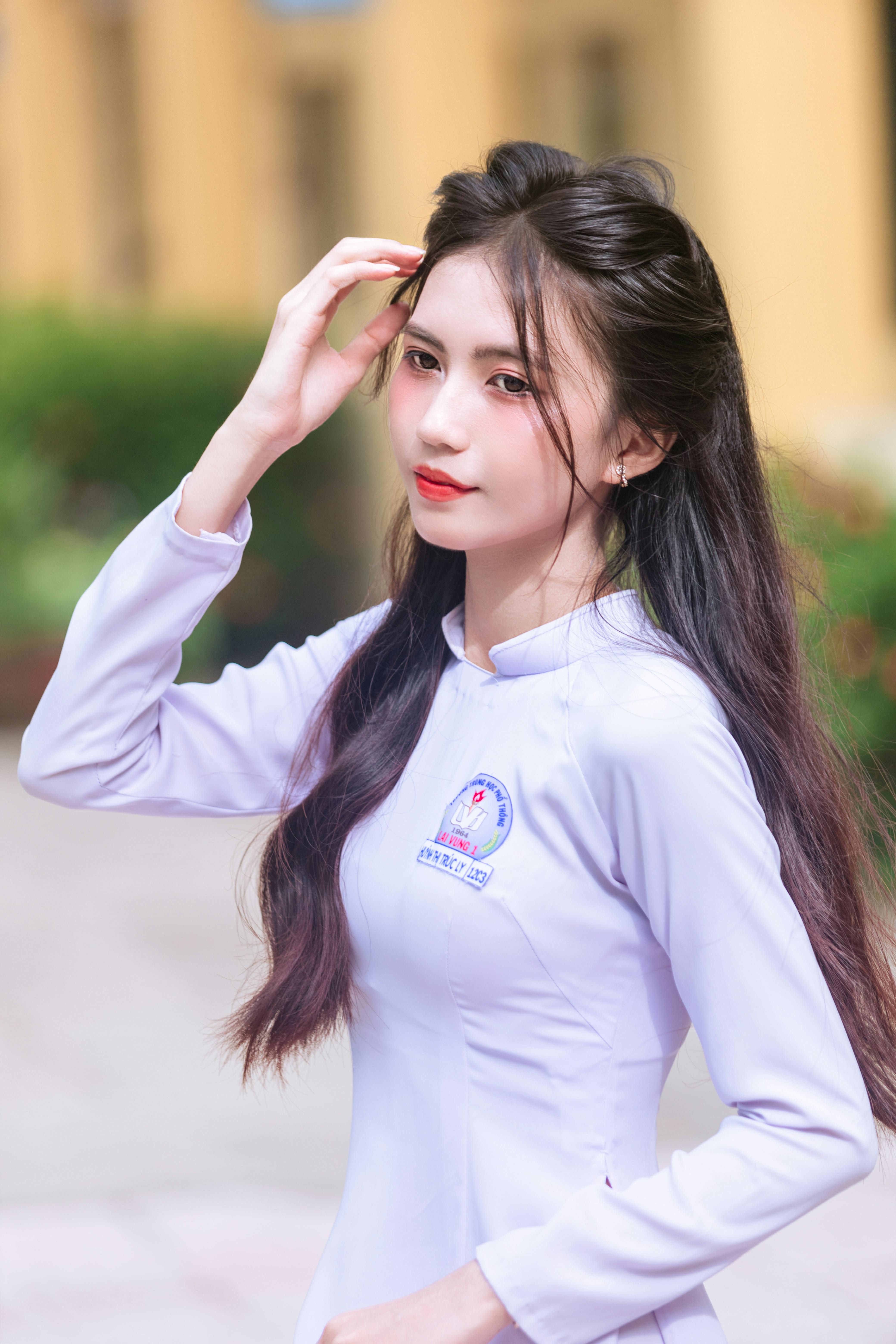 A young Vietnamese woman poses gracefully in a white ao dai. The soft natural light enhances her elegance.